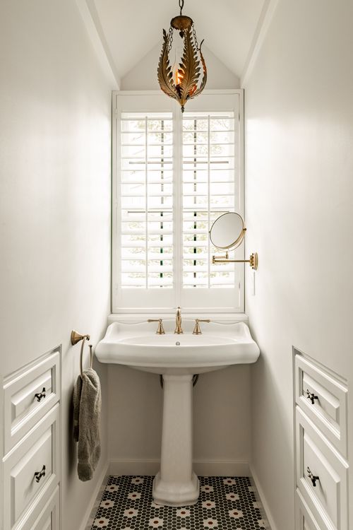 Powder room with brass fixtures, a pedestal sink and patterned penny tile floor