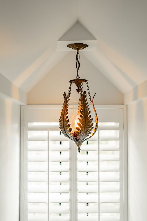 Close-up of an ornate brass leaf-shaped pendant light against a vaulted ceiling