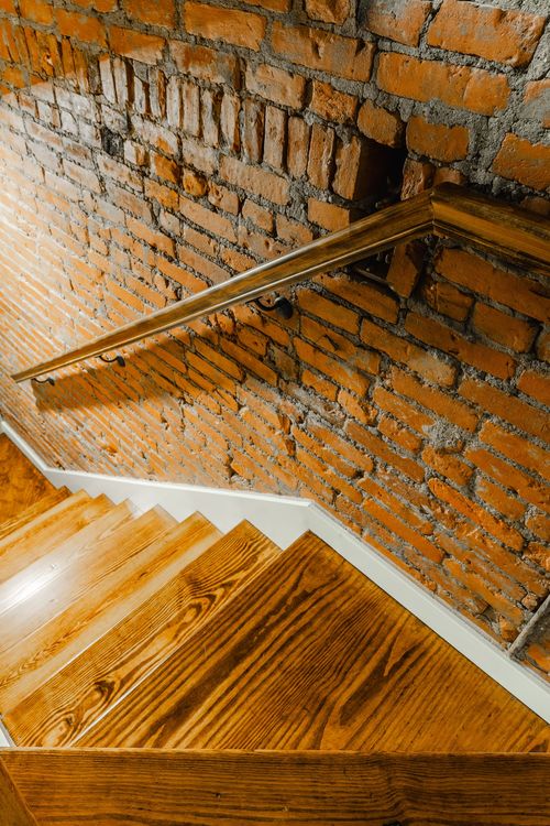 Close-up of a wood handrail bracket mounted on an exposed brick wall