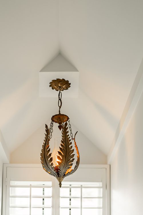 Close-up of a brass leaf pendant light fixture hanging from a peaked ceiling