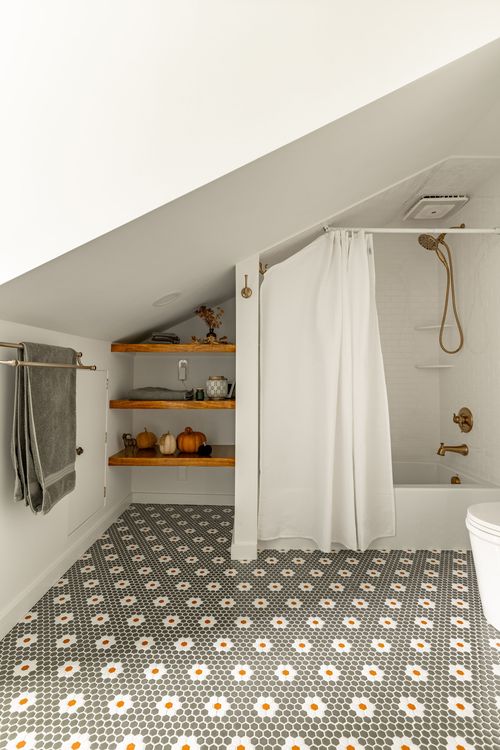 Bathroom with wood corner shelves of fall decor beside a curtained tub