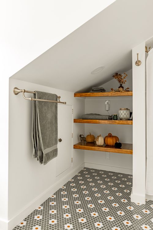 Wood floating corner shelves with towels and pumpkin decor over penny tile floor