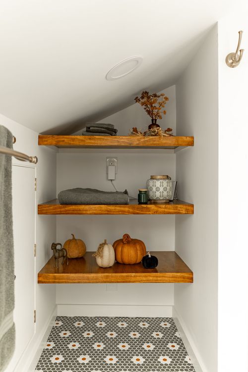 Close-up of a wood floating shelf styled with a folded towel and candle