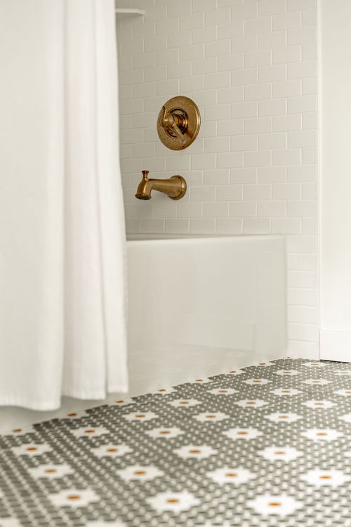 Close-up of a brass shower valve and spout against white subway tile