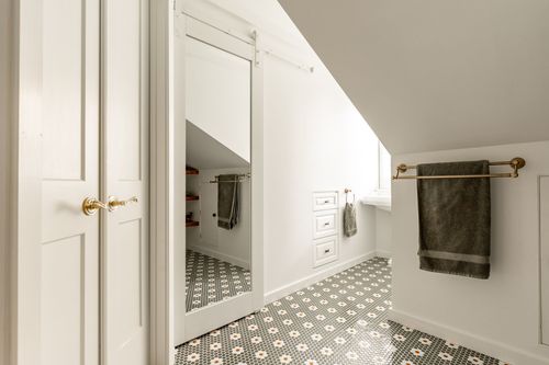 Hallway with a mirrored barn door open to a walk-in closet and hexagon tile floor