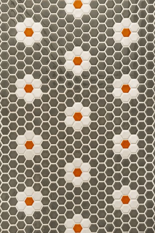 Close-up pattern of gray and white hexagon penny tile with an orange floral motif