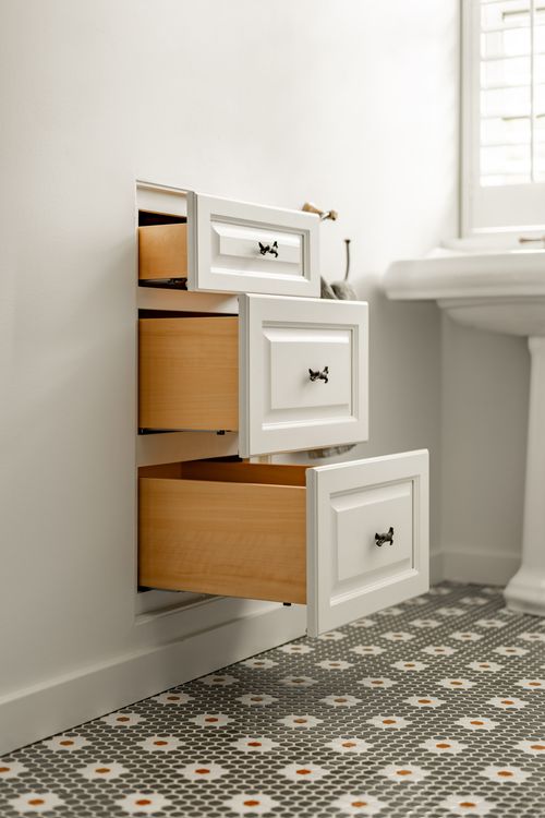 Built-in cabinet with three open drawers showing wood interiors and animal-shaped pulls