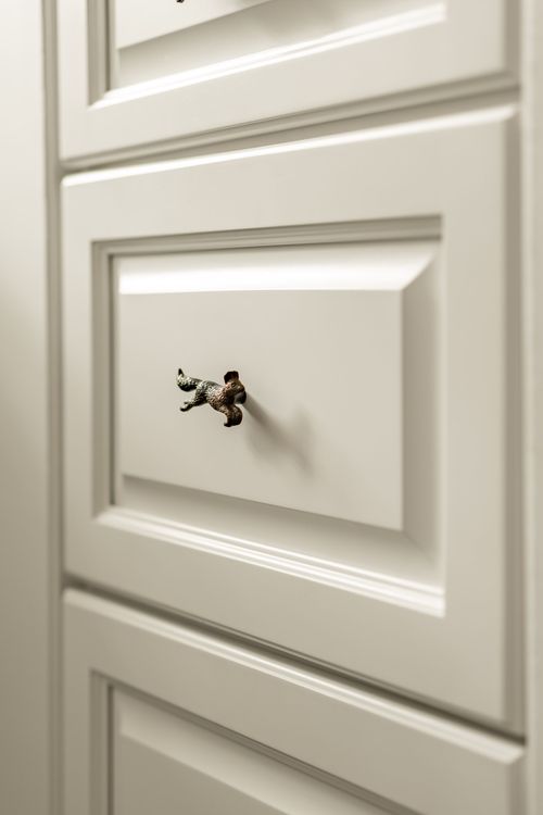 Close-up of a bronze running fox drawer pull on cream cabinetry