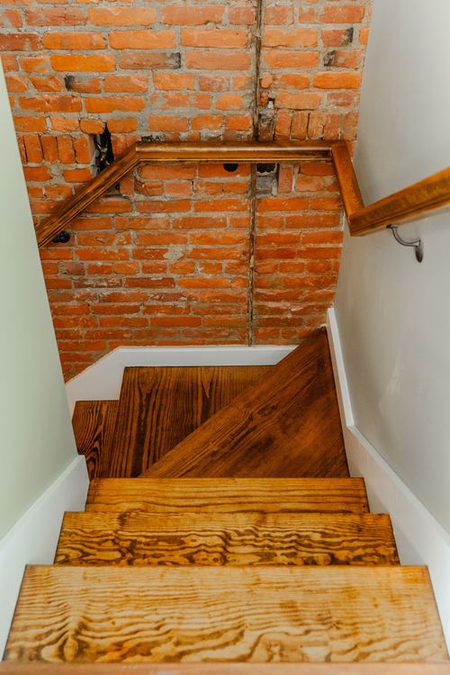 Close-up of an exposed brick wall with a rustic vertical pipe and rosette
