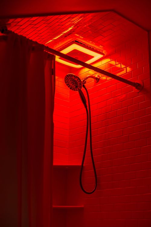 Walk-in shower with red LED mood lighting and exposed showerhead hardware