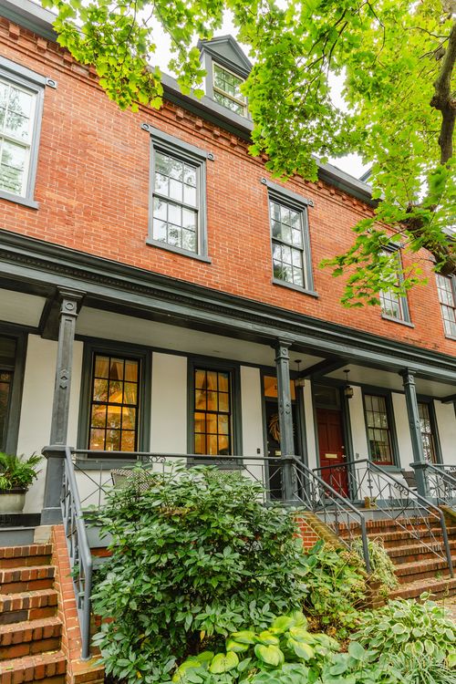 Row of brick townhomes with covered porches, dark trim and glowing porch lights