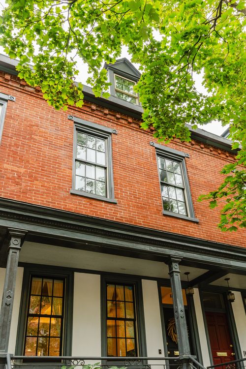 Close-up of a red brick facade with a dormer window above a covered porch
