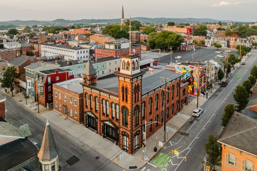 Aerial view of a restored red brick clock tower building anchoring a small downtown at dusk