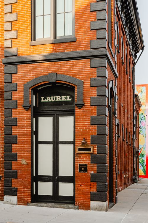 Corner brick entrance with an arched surround and Laurel signage above a black door