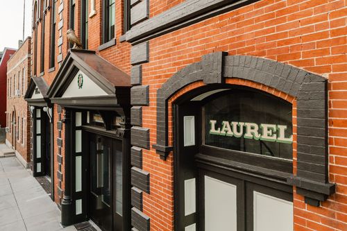 Side view of the Laurel entrance framed by a curved awning and black brick quoins