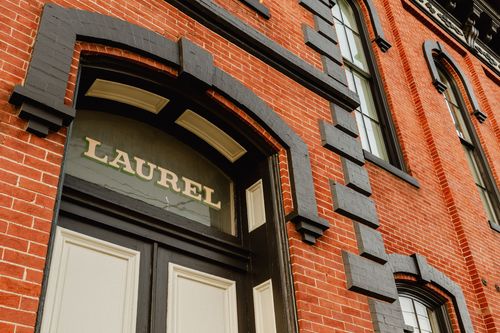 Close-up of the arched Laurel transom sign framed in black-painted brick
