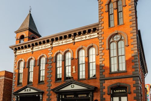 Angled view of the brick building showing its corner turret and rows of arched windows