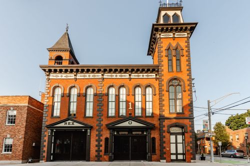 Front elevation of the brick building with a tall corner tower topped by an open cupola