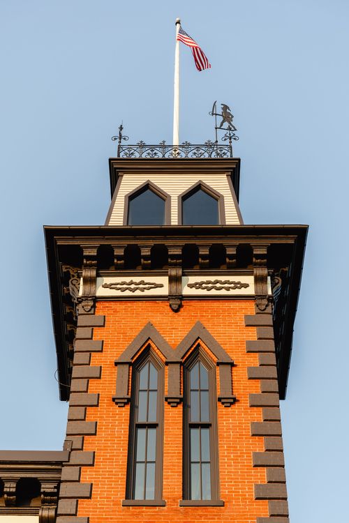 Upward view of a rooftop cupola with an American flag and a running-figure weathervane