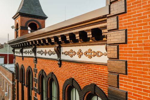 Angled view of decorative cornice brackets along the roofline with a corner turret beyond
