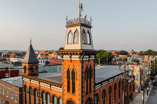 Elevated view of the tower's cupola and weathervane above rooftops at golden hour