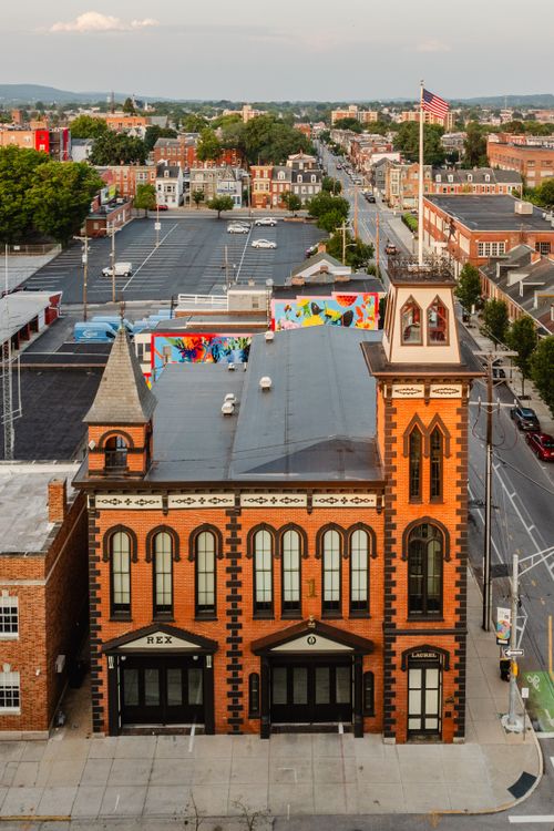 Aerial view of a red brick tower building beside a parking lot and distant mountain ridge