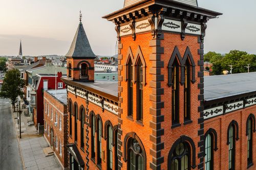 Elevated golden-hour view of the brick corner turret and tower above a small city skyline