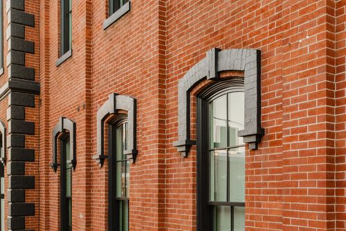 Close-up of two arched windows along a red brick wall with black-trimmed surrounds