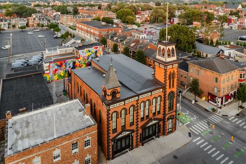 Aerial view of a brick building with black trim next to a vividly painted wall mural