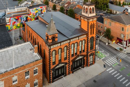 Aerial view of an ornate brick tower with arched black-framed windows above a city street