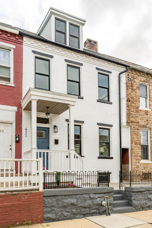White brick rowhome with black-trimmed windows, a slate-blue front door and covered porch