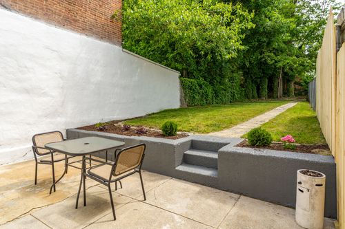Backyard patio with a metal bistro table and chairs beside raised concrete planter beds