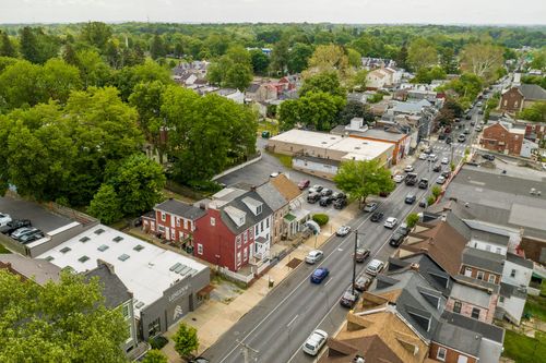 Aerial view of a small-town main street lined with brick rowhomes, storefronts and traffic