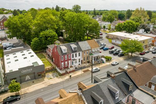 Aerial view of a brick corner building and rowhomes near a downtown parking lot