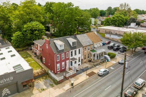 Aerial view of a red brick townhome row with rooftops along a tree-lined street
