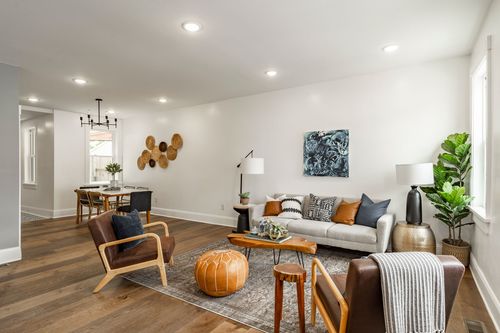 Living room with a light gray sofa, tan leather accent chairs and an orange leather pouf