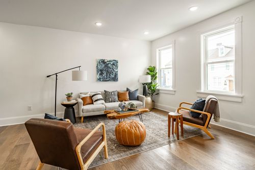 Living room with abstract blue wall art above a gray sofa and tan leather accent chairs