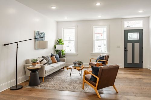 Living room with leather accent chairs near a slate front door and hardwood floors