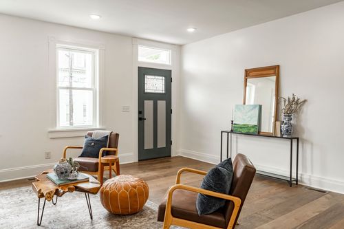 Entryway with a slate-blue front door, leather chairs and a mirrored console table