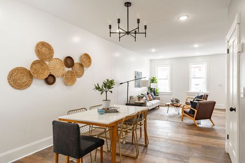 Open-concept dining and living space with woven basket wall art and hardwood floors