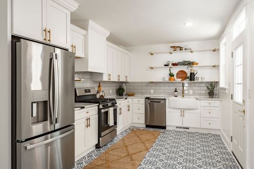 White kitchen with a farmhouse sink, open shelving and blue-and-white patterned tile floor