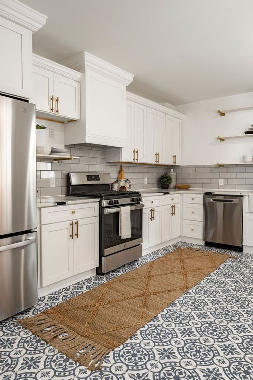 White kitchen with brass hardware, subway tile and a jute runner over patterned tile floor
