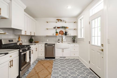 Kitchen view toward a glazed back door, open wood shelving and a white farmhouse sink