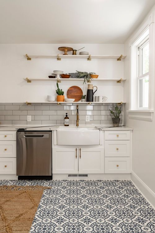 Open kitchen shelving styled with pottery and plants above a farmhouse sink