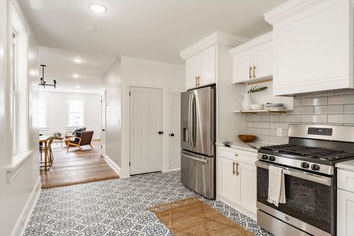 View from a white kitchen down a hallway toward a sitting area with leather chairs