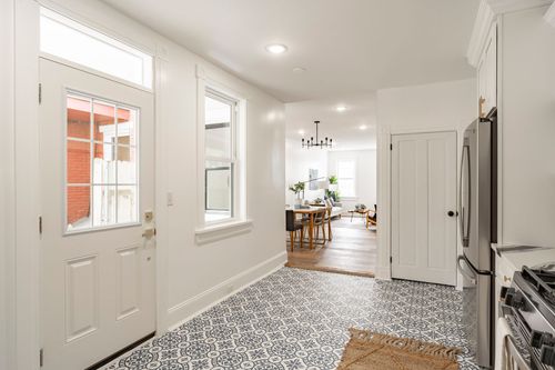 Entry hallway with a white front door and patterned tile floor leading to the dining room
