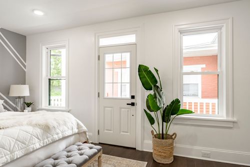 Bedroom corner with a glass-paneled door, potted plant and gray tufted bench