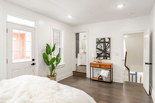 Bedroom with a doorway to an ensuite bathroom and a console table styled with art