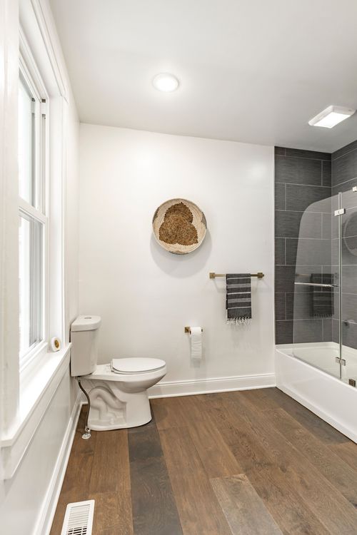 Bathroom with a white toilet, woven basket wall art and a striped hand towel