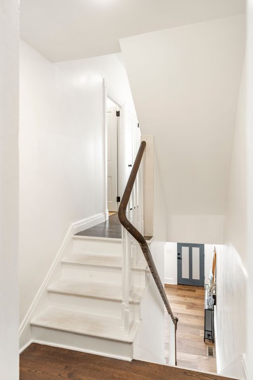 Staircase down to a slate-blue front door with a dark wood handrail